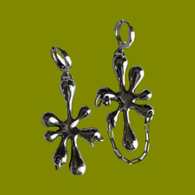 Load image into Gallery viewer, Two silver slime shaped earrings with chain and a piercing on a green background