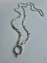 Load image into Gallery viewer, A silver-toned metal chain necklace with a figure-eight curb link design and a large circular ring clasp, displayed on a neutral light gray background.
